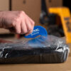 Close-up shot of someone cutting a bag with the blue Raze bag cutter