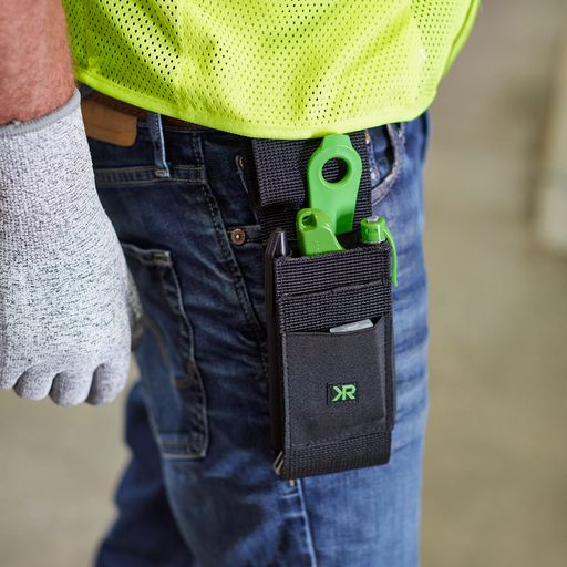 Close-up view of the AP100 holster on someone’s belt carrying a knife, two pens, and a pack of replacement blades